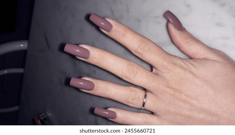 A womans hand adorned with a ring on her finger, showcasing long nails painted in a vibrant magenta and violet nail polish, a symbol of her exquisite manicure and attention to nail care - Powered by Shutterstock