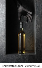 A Woman's Hand In A Black Glove Reaches For A Bottle Of White Wine. A Concept Image On The Theme Of Expensive Wines.