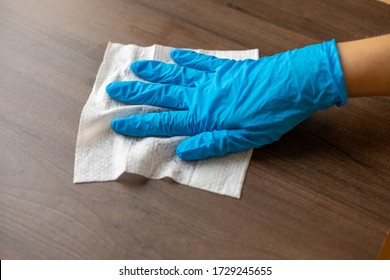 Woman's Hand In Blue Gloves Sanitizing Cleaning Home Office Wood Table Surface With Wet Wipes