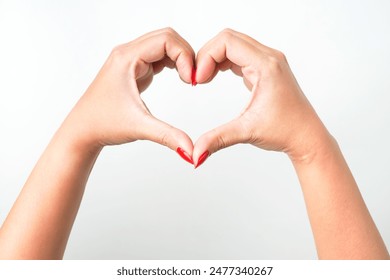 A woman's hand with bright red nail polish forms heart shape gesture as a sign of love and romance. - Powered by Shutterstock