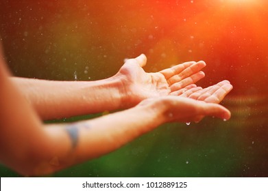 Womans hand catch rain drops on blurred background. Sun light fall wet touch. Reiki heal energy, god bless hope, care poor world, soul aura pray help, ask peace give back, good fun day in life concept - Powered by Shutterstock