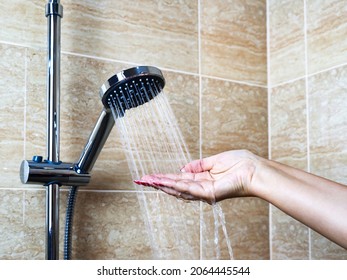 Woman's Hand Check Water Temperature In The Shower With Hand Shower Wall.