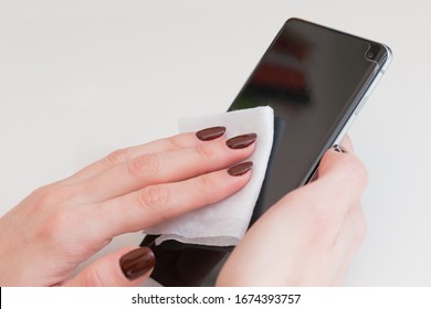 Womans Hand Cleaning Smartphone Screen With Alcohol. Concept Of Cleaning Dirty Screen Phone For Disease Prevention From Virus Covid-19.