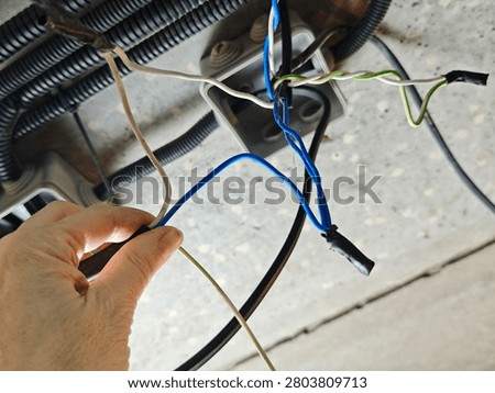 Woman's hand connects multiple electrical wires in a junction box for home electrical installation and power distribution tasks.