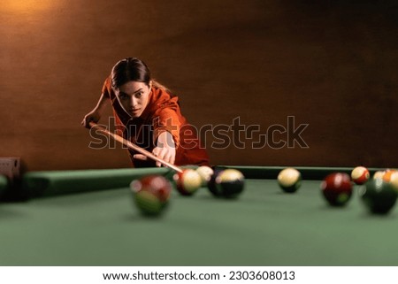 Woman's hand with cue pointing at billiard ball at table. Playing billiards concept