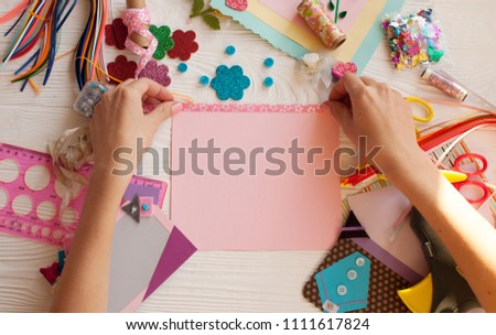 Woman's hand cut paper, scrapbooking for wedding or other festive decorations . Tools for scrapbooking.
