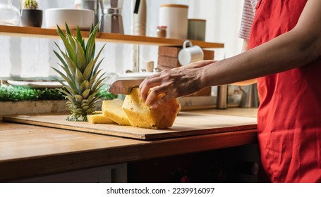 woman's hand cutting pineapple in the kitchen, using tropical fruit for fresh juice. - Powered by Shutterstock