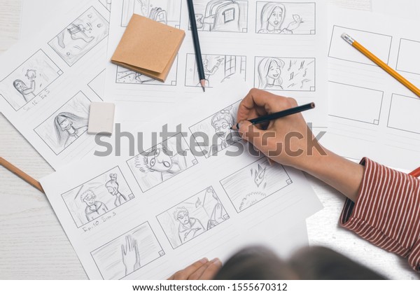 Woman\'s\
hand draws a storyboard for a film or\
cartoon.