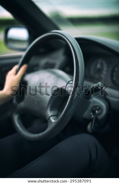 Woman\'s hand\
driving a car. Unrecognizable\
person.