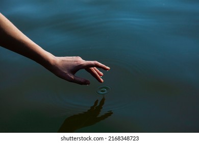 a woman's hand gently touches the water in the pond, a close horizontal photo on the theme of tranquility - Shutterstock ID 2168348723