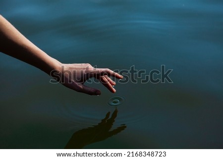 a woman's hand gently touches the water in the pond, a close horizontal photo on the theme of tranquility 商業照片 © 