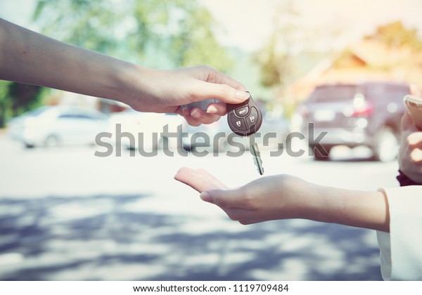 Woman\'s\
hand give the car key and blurred\
background.