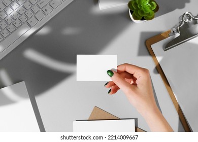 Woman's hand giving businesscard above the working table