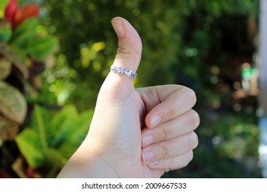 A Woman's Hand Giving A Thumbs Up With A Ring On Her Thumb. 