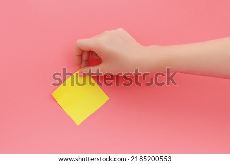 Woman's hand glues yellow sticker or sticky post-it notes on pink background. ストックフォト © 