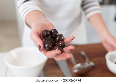 Woman's Hand Grabbing Black Olives For Cooking. Homemade Food Concept