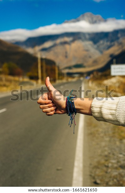 Woman\'s hand in hitch hiking sign to ask for a\
car as passenger.