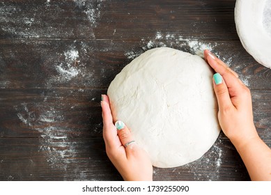 Woman's Hand Hold Fresh Dough And Cutter Scraper For Preparing Homemade Bread On A Wooden Dark Background.