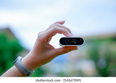 Woman's hand holding air pollution monitor PM 2.5 concept, fresh air life.	 - Powered by Shutterstock