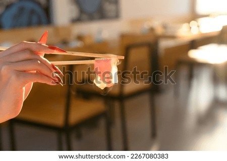 Woman's hand holding bacon with chopsticks