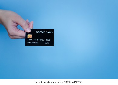 Woman's Hand Holding The Black Credit Card On Cerulean Background For Shopping Online. 