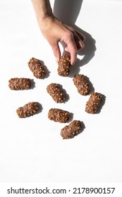 Woman's Hand Holding Chocolate Candy Bar On White Background. Top View, Flat Lay.