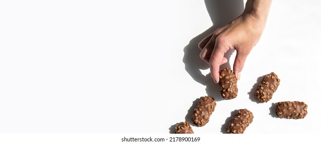 Woman's Hand Holding Chocolate Candy Bar On White Background. Top View, Flat Lay. Banner.