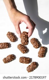 Woman's Hand Holding Chocolate Candy Bar On White Background. Top View, Flat Lay.