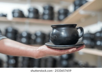 Woman's hand holding clay cup with saucer on blurred background - Powered by Shutterstock