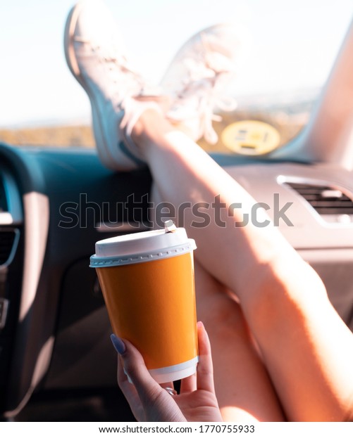 woman\'s hand holding\
coffee inside a car