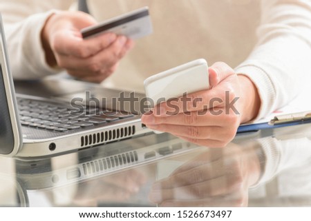 Womans hand holding credit card and smartphone over notebook, concept of e-commers and mobile payment