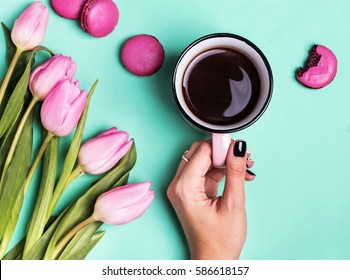 Woman's Hand Holding Cup With Coffee And Pink Tulips, Top View.