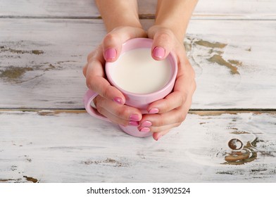 Woman's Hand Holding Cup Of Milk. Top View