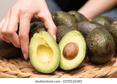 Woman's hand holding a cut avocado - Shutterstock ID 2370126583
