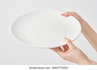 Woman's hand holding an empty plate - Powered by Shutterstock