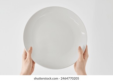 Woman's hand holding an empty plate - Powered by Shutterstock