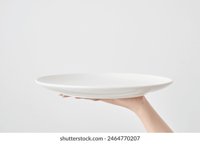 Woman's hand holding an empty plate - Powered by Shutterstock