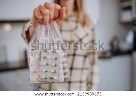 Woman's hand holding expired pills ready to recycle.