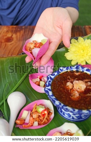 Woman's Hand Holding Fresh Lotus Petal Wrapped Appetizer before Putting Spicy Dip