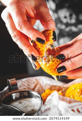 Woman's hand holding fried mozzarella cheese ball
