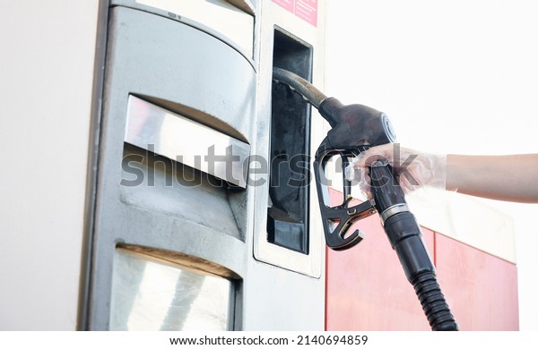 Woman\'s hand holding a fuel hose while refueling\
at a gas station during the energy crisis and the rise in the price\
of gasoline and diesel.