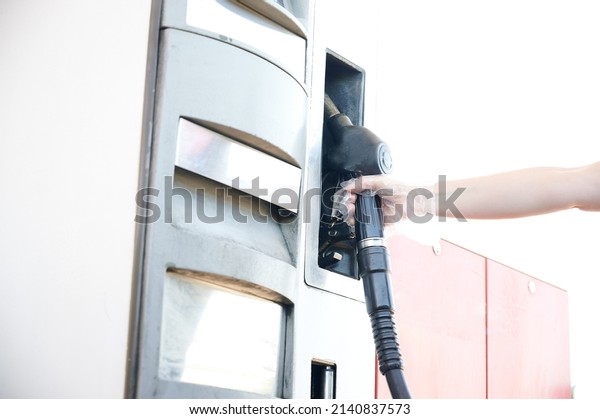 Woman\'s hand holding a fuel hose while refueling\
at a gas station during the energy crisis and the rise in the price\
of gasoline and diesel.