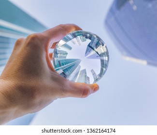 Woman's hand holding the glass ball  with skyscrapers reflection. Moscow International Business Center reflection in the transparent glass sphere look up   