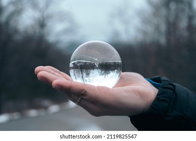 Woman's Hand Holding A Glass Ball In The Forest