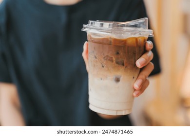 A woman's hand is holding a glass of iced latte coffee. - Powered by Shutterstock