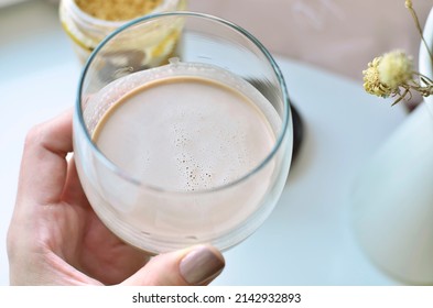 Womans Hand Holding A Glass With Unsweetened Powdered Peanut Butter Shake