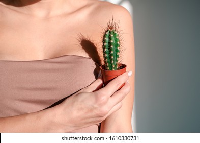 Woman's hand holding green cactus near her armpit,Depilation concept. Body positive concept. Concept of not shaving.