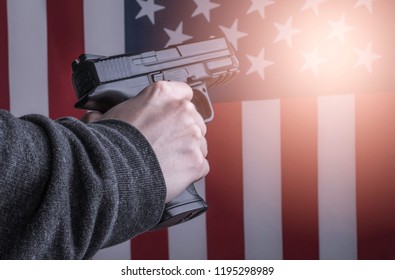 Woman's Hand Holding Gun On Flag Of USA Background. Gun Violence In The United States Of America Concept Photo. 