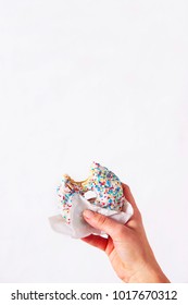 Woman's Hand Is Holding A Half Eaten Bagel In Front Of White Background. Sweetness And Happiness Concept. 