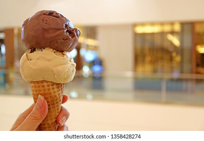 Woman's hand holding ice cream cone with two scoops of chocolate and peanut butter ice - Powered by Shutterstock